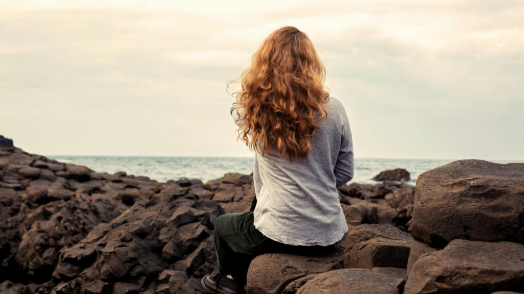 une femme assise face à la mer symbolisant la solitude, prix relationnel de la conscience